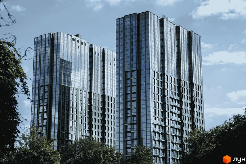 Житловий комплекс EDELDORF HILLS з панорамними вікнами та високими корпусами на тлі дерев і неба.