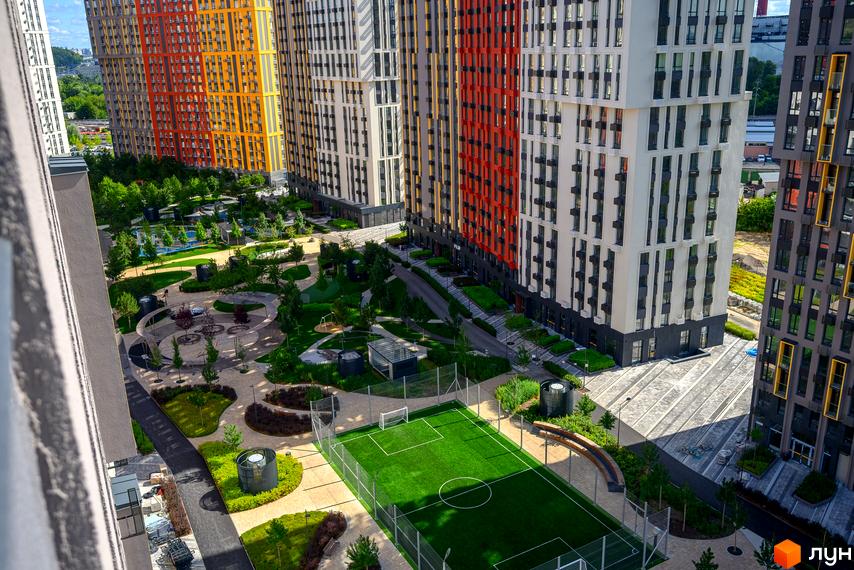 Високі багатоповерхові будинки ЖК Svitlo Park та затишний двір з футбольним полем та зонами для відпочинку.