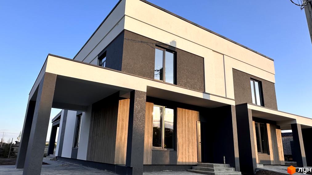 Двоповерховий котедж з панорамними вікнами та навісом для авто в КМ Dibrova Park перед замощенням тротуарною плиткою.