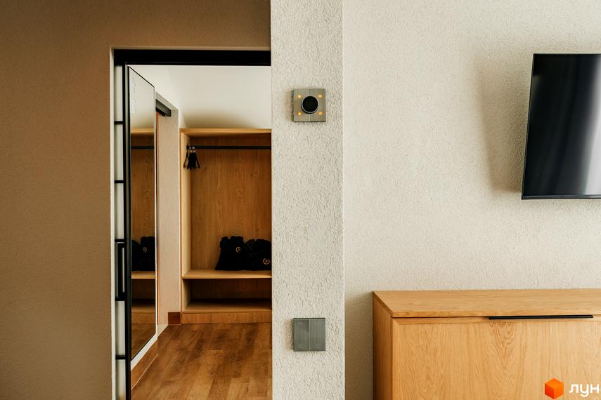 Інтер'єр передпокою в котеджному містечку КМ Fomich Estates із вбудованою шафою та телевізором.