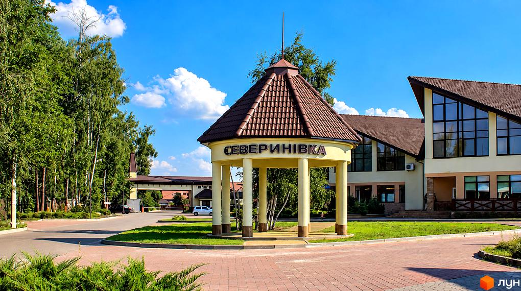 Котеджне містечко КМ Северинівка. Зовнішній вигляд будівель та вхідна група з навісом. Прибудинкова територія з деревами та газоном.