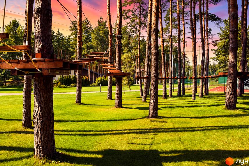Мотузковий парк на території КМ Goodlife Park серед соснового лісу та зеленого газону.