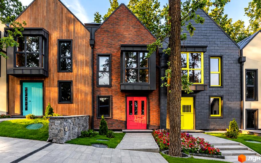 Котеджне містечко Oak Grove Town з фасадами з дерева, цегли та плитки, з яскравими дверима та доглянутою прибудинковою територією.