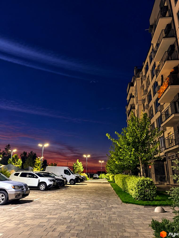 Житловий комплекс Park Residence ввечері: багатоповерховий будинок з балконами та освітлена прибудинкова територія з парковкою та зеленими насадженнями.