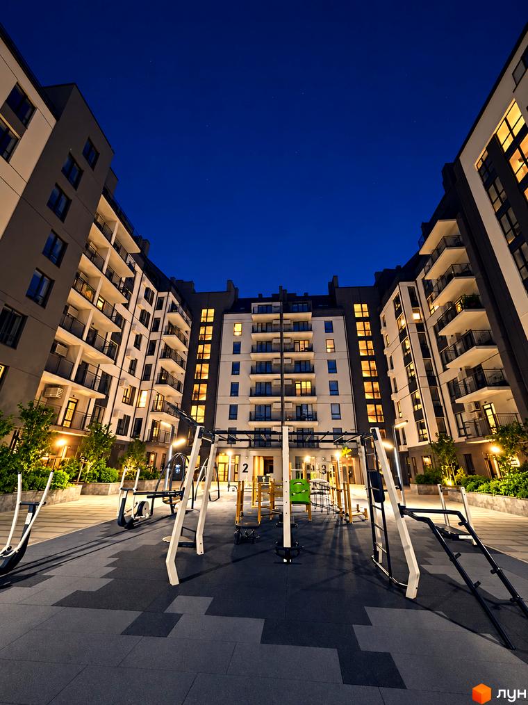 Багатоповерхові будинки житлового комплексу Park Residence з підсвічуванням фасадів. Обладнаний спортивний майданчик у нічному дворі.