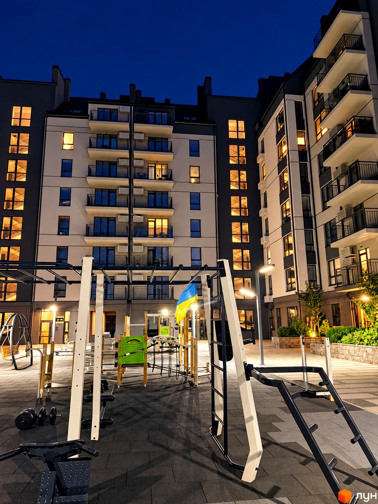 Житловий комплекс Park Residence вночі з освітленими вікнами та балконами, а також облаштованим спортивним майданчиком у дворі.
