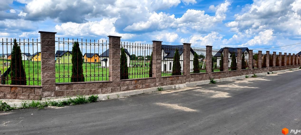 Котеджне містечко КМ Лелека: огороджена прибудинкова територія та двоповерхові будинки з двомаскатними дахами на зеленому газоні.