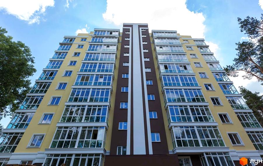 Фасад житлового комплексу Полтавський з великою кількістю скління та балконів. Будинок має жовто-коричневе забарвлення фасаду та білу вертикальну смугу.