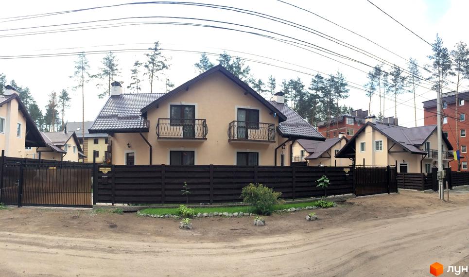 Новобудова на вулиці Патона. Сучасні будинки з коричневими дахами та світлими фасадами, огороджені темним дерев'яним парканом. На подвір'ї зелені насадження та доглянута територія.