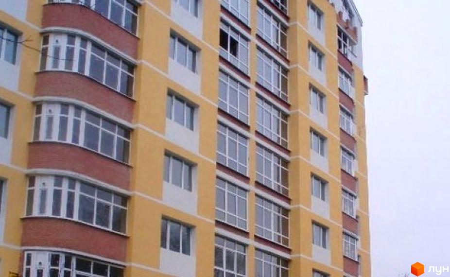 Фасад житлового комплексу на вул. Берестовська (Пушкіна), 22, з жовтими та цегляними елементами. Багатоповерхова будівля з численними вікнами та балконами.