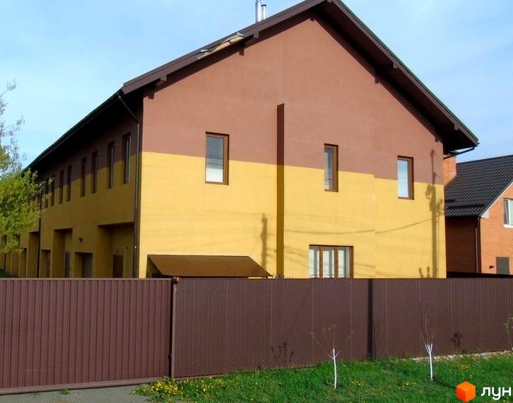 Зовнішній вигляд двоповерхових таунхаусів у коричнево-жовтих кольорах з коричневим парканом та зеленою травою. Townhouse Петрівський - комфортне житло для вашої родини.