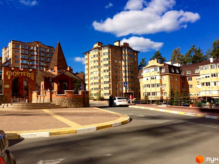 Житловий комплекс Південний: багатоповерхові будинки жовтого кольору з коричневими дахами, вхідна група з цегли та аркою з написом 