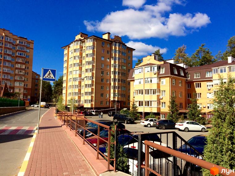 Житловий комплекс Південний: жовті багатоповерхові будинки з коричневими дахами, зелені насадження та парковка біля будинку.