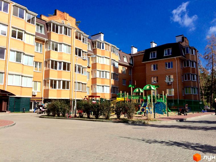 Житловий комплекс Південний. Зовнішній вигляд цегляних будинків з балконами та дитячим майданчиком на прибудинковій території.