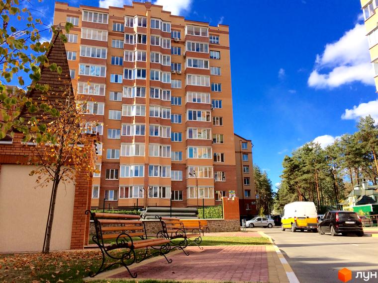 Житловий комплекс Південний. Багатоповерховий будинок з цегляним фасадом та великою кількістю вікон. Поруч розташовані лавки та дерева.