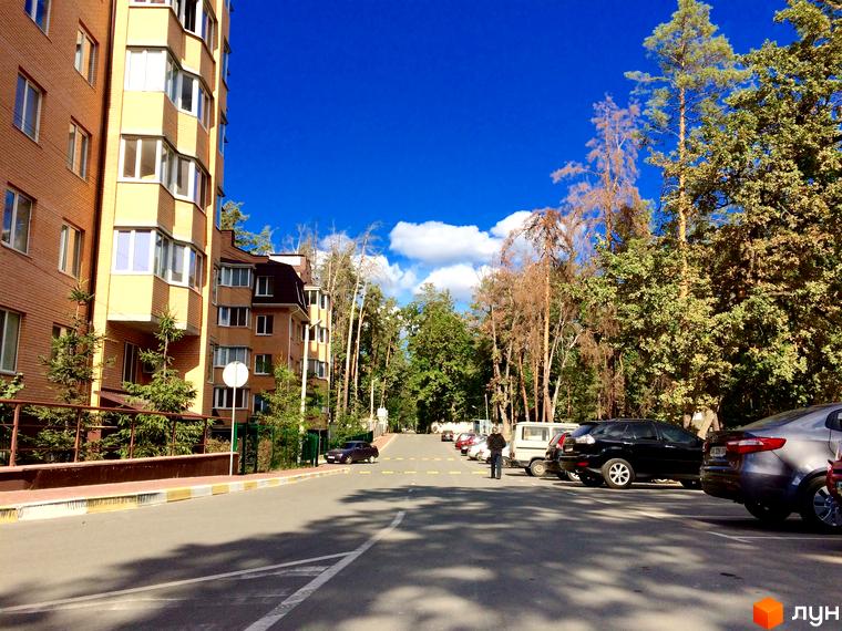 Житловий комплекс Південний з цегляним фасадом та балконами. Прибудинкова територія з дорогою та деревами.
