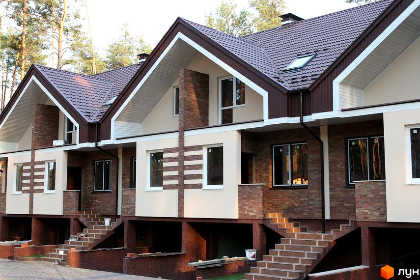 Зовнішній вигляд новобудови на вул. Гоголя, 12в. Фасад оздоблений каменем та штукатуркою, з коричневим дахом та білими елементами. Поруч сходи та прибудинкова територія.