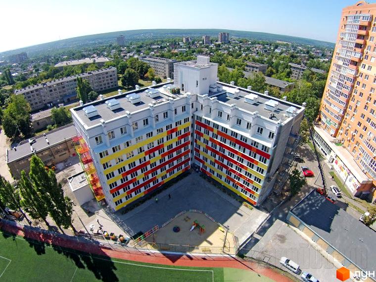 Житловий комплекс Олексіївські Акварелі – яскрава багатоповерхова новобудова з червоно-жовтими фасадами, розташована біля футбольного поля та дитячого майданчика.