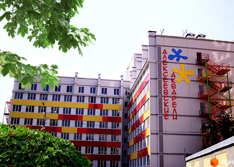 Житловий комплекс Олексіївські Акварелі з яскравим фасадом та червоними зовнішніми сходами, оточений зеленню.