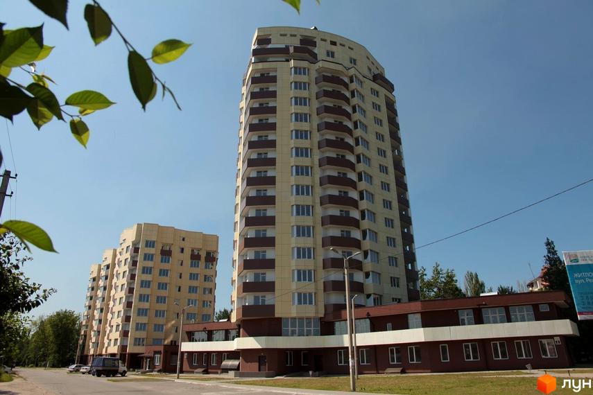 Житловий комплекс Олександрівський посад: висотні будинки з коричневими балконами та світло-бежевими фасадами. Поруч розташовані нижчі будівлі та зелені насадження.