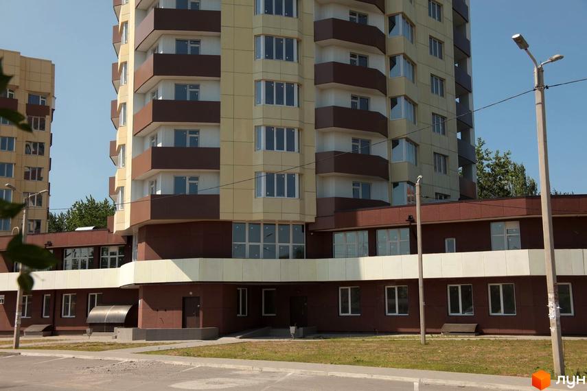 Житловий комплекс Олександрівський посад: фасади будівель з балконами та великими вікнами, прибудинкова територія з газоном та парковкою.