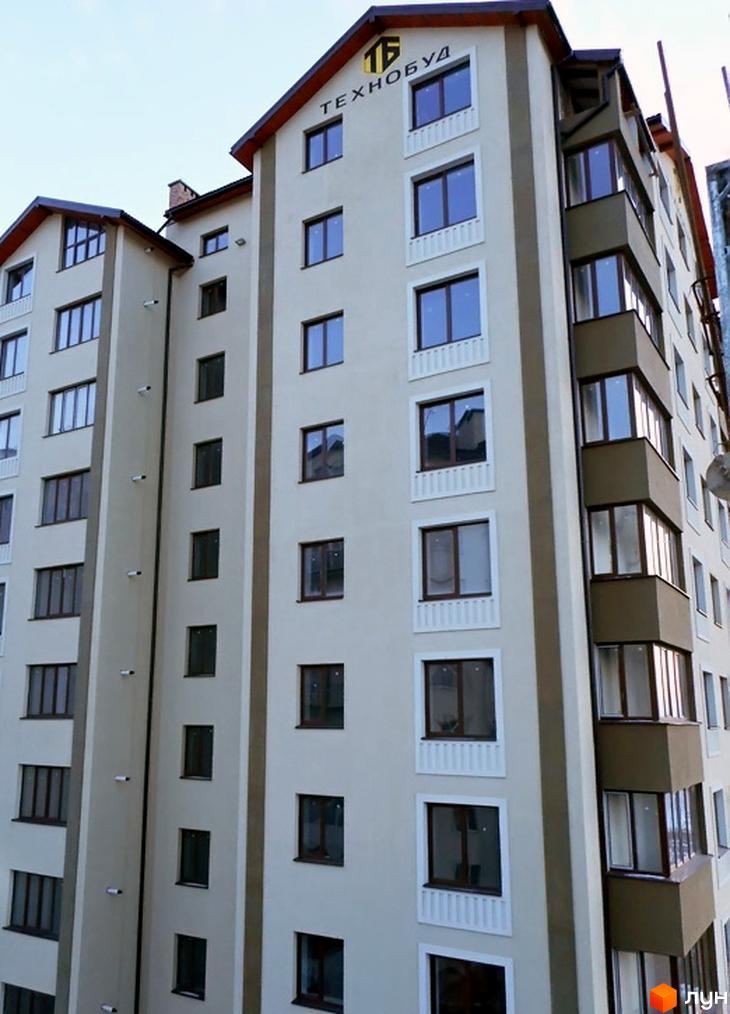 Зовнішній вигляд фасаду житлового комплексу Молодіжний. Багатоквартирний будинок з коричневими та бежевими елементами та численними вікнами.