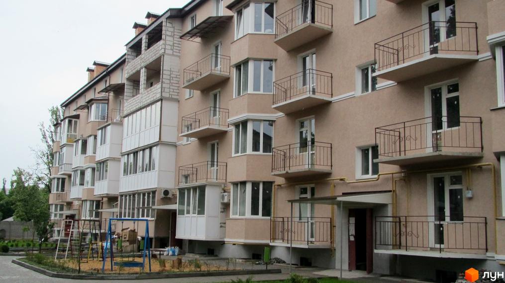 Зовнішній вигляд фасаду житлового комплексу на вул. Кузнецька (Скороходова), 56а, з балконами та вікнами. Прибудинкова територія з дитячим майданчиком.