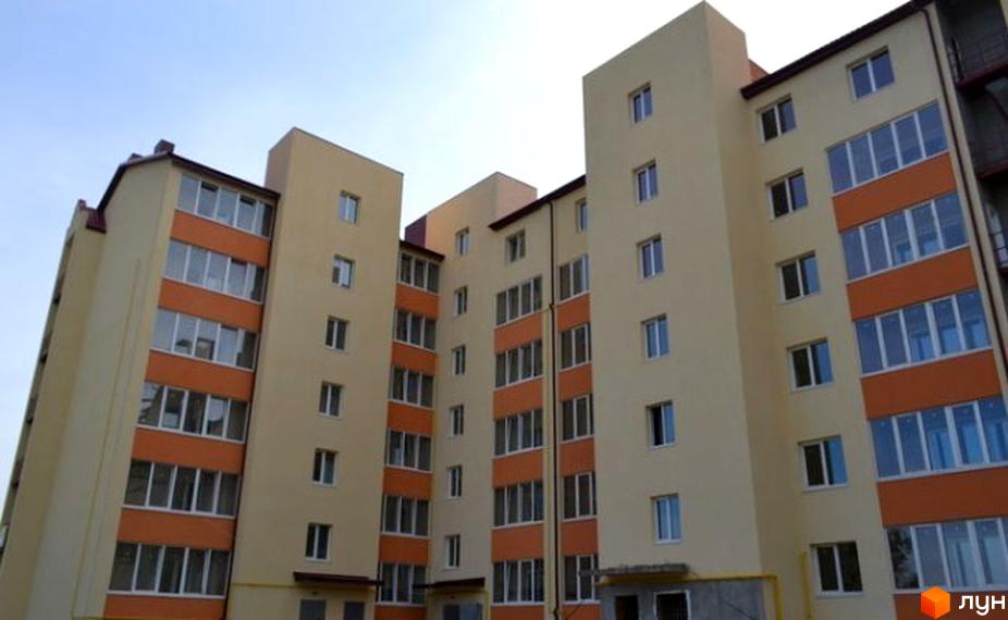 Фасад новобудови на вул. Ясна, 7б. Багатоповерховий житловий комплекс з яскравими помаранчевими елементами та великими вікнами.