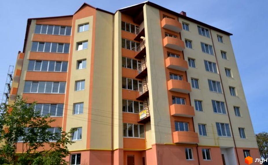 Фасад житлового комплексу на вул. Ясна, 7б. Багатоповерхова новобудова з балконами та великими вікнами, оздоблена в помаранчевих та бежевих тонах.