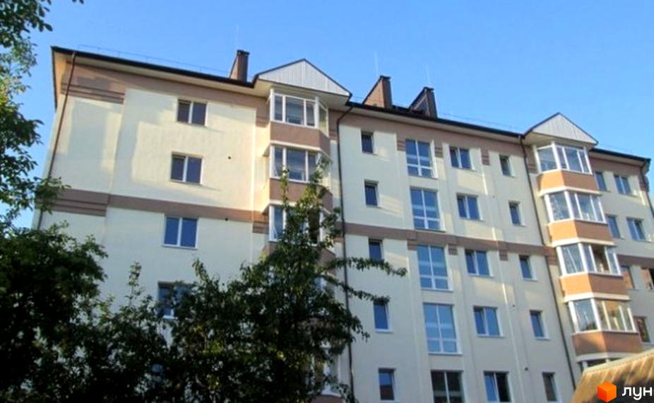 Житловий комплекс на вул. Литовська, 77. Видно світлий багатоповерховий будинок з коричневими акцентами, численними вікнами та заскленими балконами, оточений зеленню.