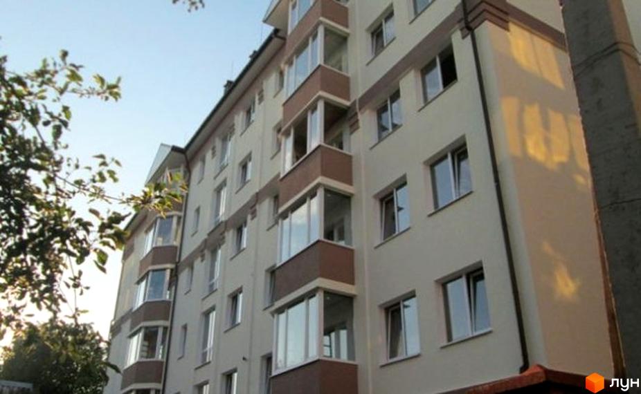 Багатоповерховий житловий будинок світлого кольору з коричневими балконами та заскленими лоджіями на вул. Литовська, 77, оточений зеленню.