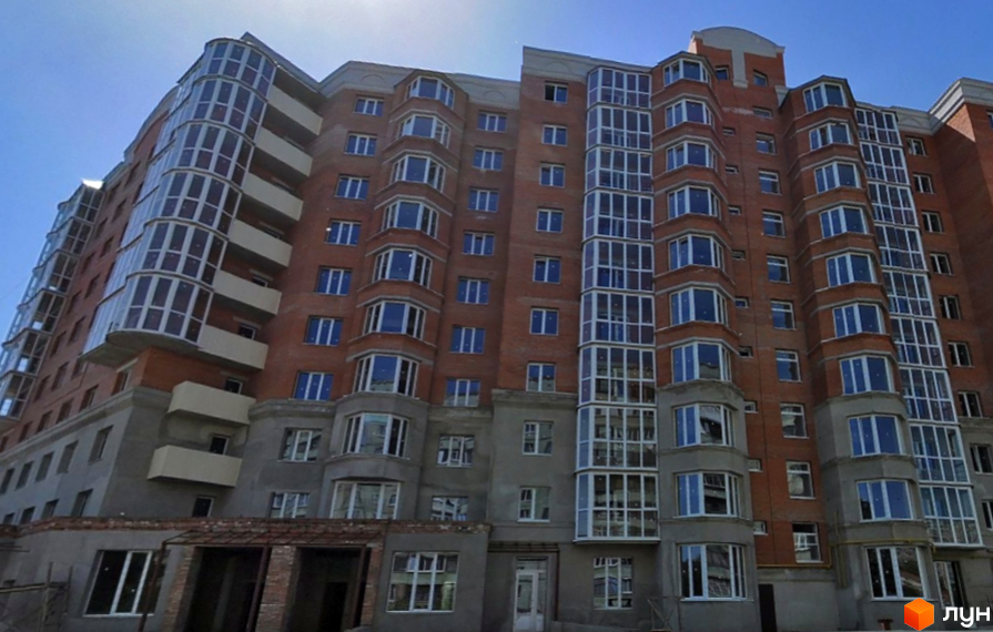 Багатоповерховий житловий комплекс з червоної цегли, заскленими балконами та еркерами на вул. Олександра Бідного, 20.