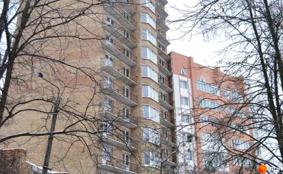 Житловий комплекс Беркут: цегляний багатоповерховий будинок з балконами та інша будівля світло-персикового кольору, крізь голі дерева.
