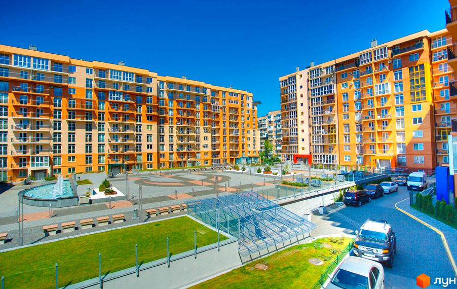 Житловий комплекс Водограй: багатоповерхові будинки з помаранчевими та світлими фасадами, доглянута прибудинкова територія з фонтаном та зеленими насадженнями.