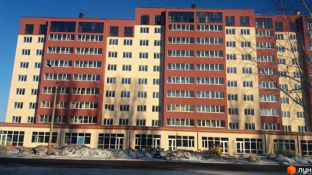 Фасад житлового комплексу Другий Парковий з цегляними та бежевими елементами. Навколо новобудови видно засніжену територію та будівельні роботи.