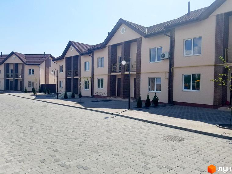 Зовнішній вигляд будинків ЖК Другий Парковий з цегляними вставками та світлими фасадами. Прибудинкова територія з бруківкою та зеленими насадженнями.