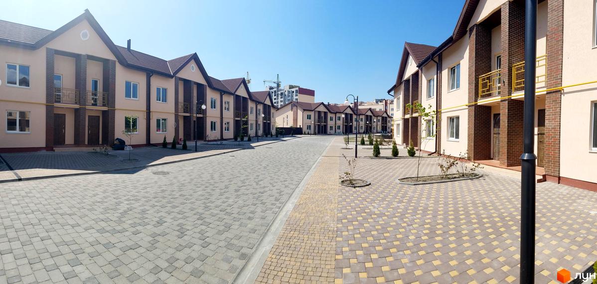 Житловий комплекс Другий Парковий: фасади двоповерхових будинків з коричневим дахом та світлими стінами, вимощені доріжки та зелені насадження. Фото новобудови.