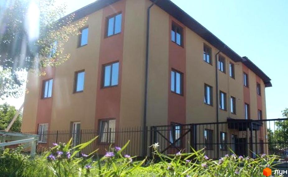 Будинок житлового комплексу на вулиці Ціолковського, 17. Фасад будівлі двоколірний, з великою кількістю вікон. Перед будинком огороджена територія з деревами та квітами.