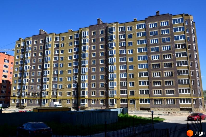 Зовнішній вигляд багатоповерхового житлового комплексу на вул. Іващенка, 1а. Навколо будинку видно прибудинкову територію з паркуванням та зеленими насадженнями.