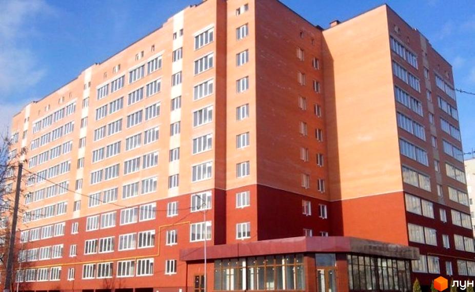 Фасад багатоповерхового житлового комплексу на вулиці Ветеранів, 22. Будинок має цегляне оздоблення та великі вікна. Навколо новобудови видно дерева та елементи прибудинкової території.