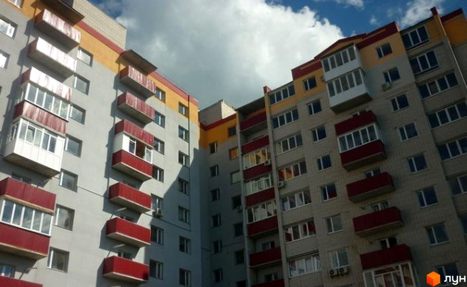 Зовнішній вигляд житлового комплексу на вулиці Старобілоуська, 61а. Багатоповерховий будинок сірого кольору з жовтими та червоними елементами, балконами та вікнами.