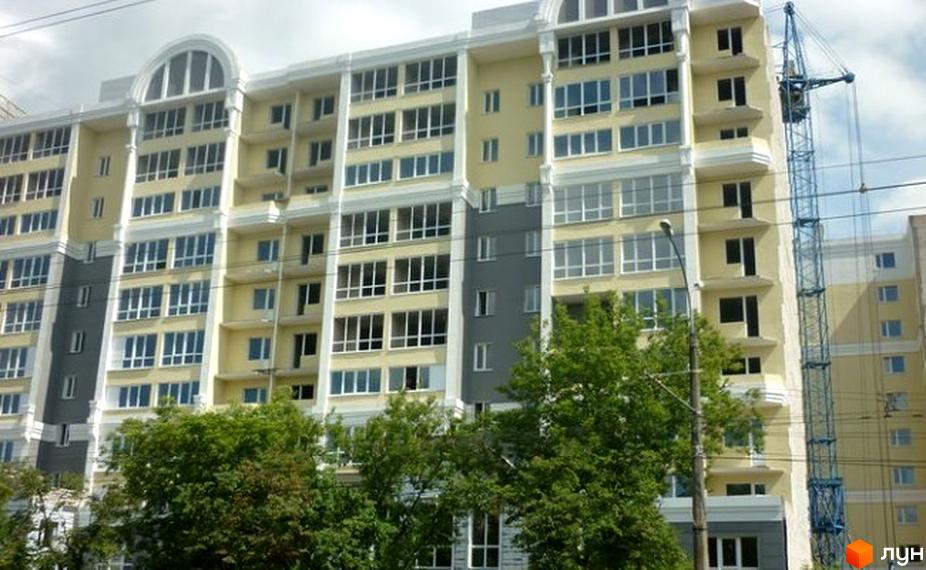 Новобудова на просп. Перемоги, 119а. Багатоповерховий будинок світло-жовтого кольору з великою кількістю вікон та балконів. Поруч видно зелені дерева та будівельний кран.