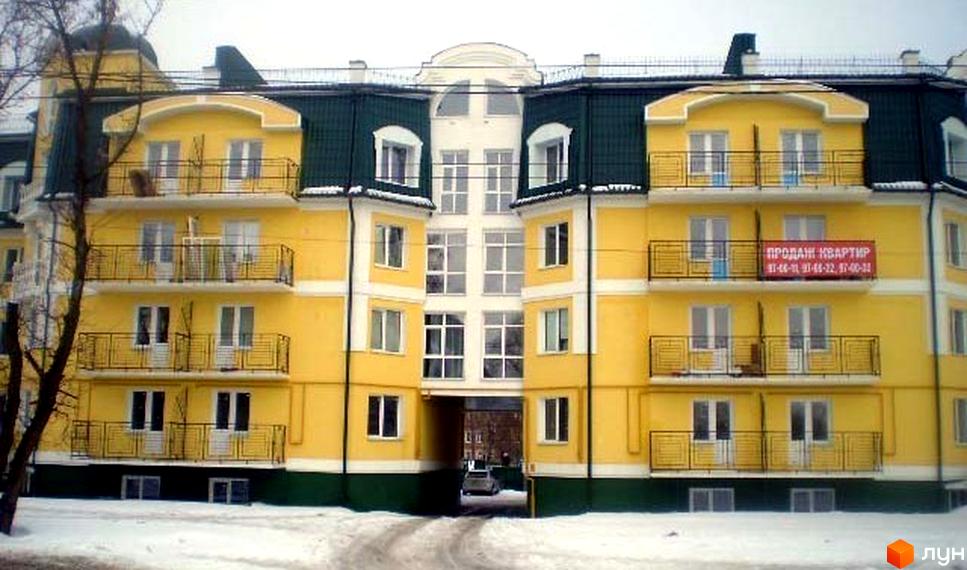 Житловий комплекс на вул. Олександра Довженка (Толстого), 125а. Зовнішній вигляд жовтої будівлі з зеленим дахом та балконами. Навколо засніжена територія.