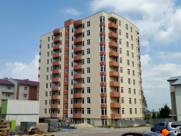 Сучасний житловий комплекс на вулиці Сахарова. Будинок має бежевий фасад з коричневими балконами, поруч розташована прибудинкова територія з паркуванням.