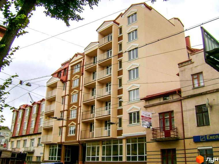 Фасад новобудови на вулиці Богдана Хмельницького. Багатоповерховий житловий комплекс з балконами та вікнами.