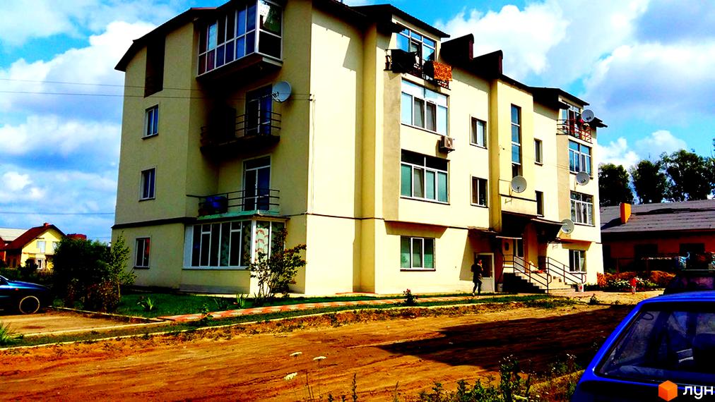 Зовнішній вигляд багатоповерхового будинку ЖК Княжицький двір з балконами та вікнами. На прибудинковій території видно зелену зону та дорогу.