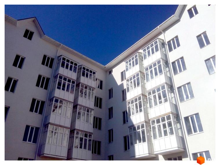 Зовнішній вигляд новобудови на вул. Дмитрівська, 19. Багатоповерховий будинок з балконами та вікнами.