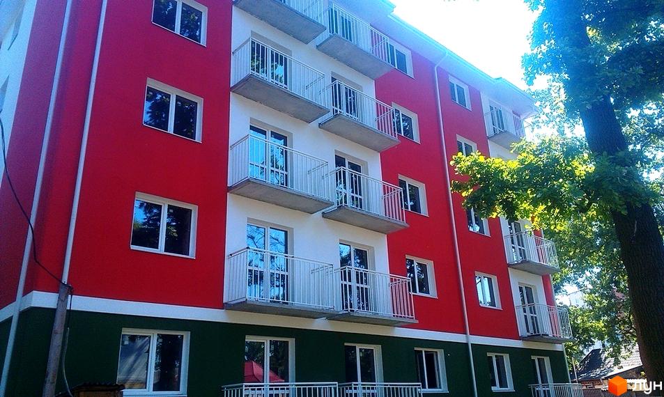 Новобудова ЖК Щасливий з червоно-біло-зеленим фасадом та балконами. Будинок оточений деревами.