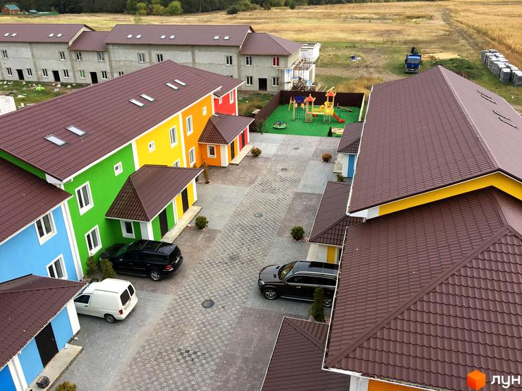 Комплекс Ivankiv-townhouse з яскравими фасадами будинків та дитячим майданчиком. Огляд новобудови з прибудинковою територією та парковкою.