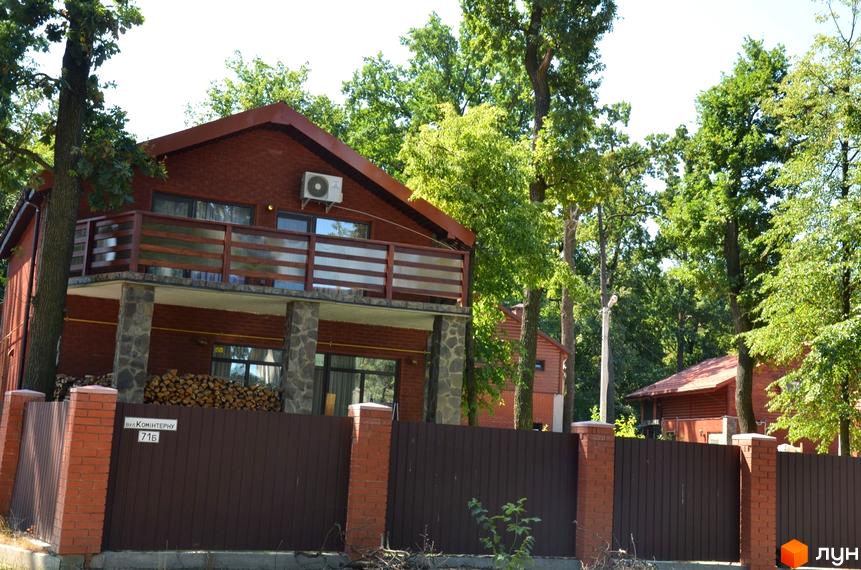 Будинок з червоної цегли з балконом та парканом. На території є дерева та інша будівля. Житловий комплекс на вул. Давидчука (Комінтерна), 71Б.